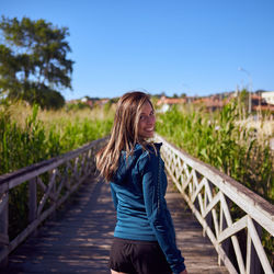 Woman standing on railing against sky