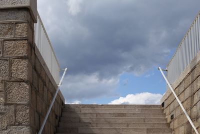 Low angle view of steps against cloudy sky