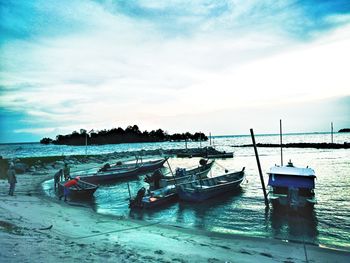 Boats moored on shore against sky