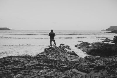 Full length of man on rock at beach against clear sky