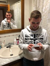 Young man wearing sunglasses standing in bathroom