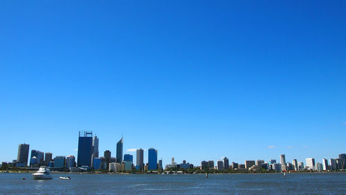 City at waterfront against blue sky