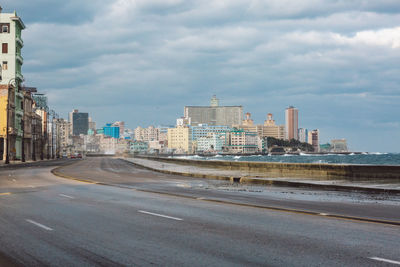 Road by buildings against sky in city