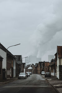 Cars on street amidst buildings in city against sky