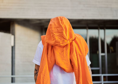 Front view of man wearing orange standing against building