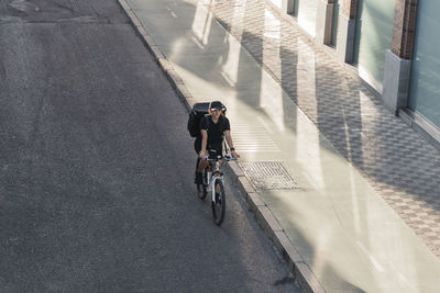 Young female frontline worker riding bicycle on road