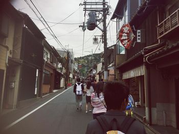 Rear view of people walking on road amidst buildings