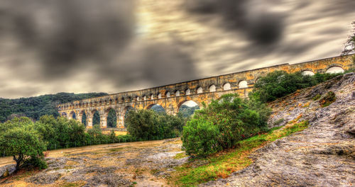 Arch bridge amidst trees against sky