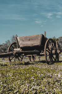 Abandoned cart on field against sky