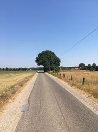 Road amidst field against clear sky