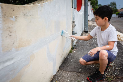 Side view of young man sitting on street