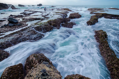 Mid distance of man standing on rock at beach