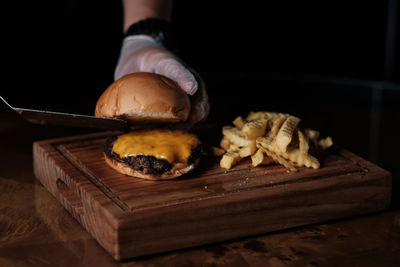Cropped hand of person eating food on cutting board