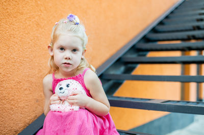 Portrait of cute baby girl standing by railing