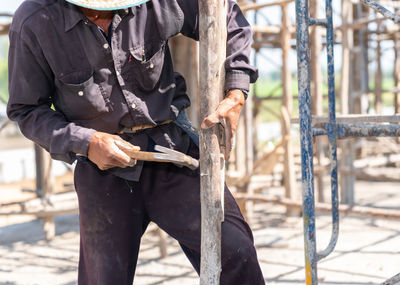 Worker hit nail on wooden stick for support scaffolding second floor in construction site.