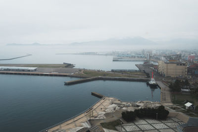 High angle view of city by sea against sky