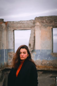 Portrait of beautiful young woman standing against wall