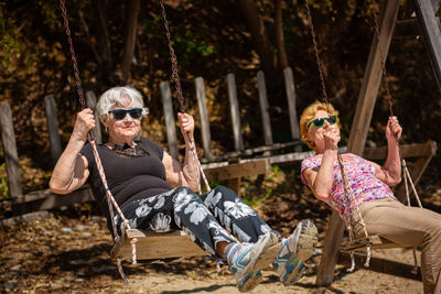 Portrait of woman sitting on swing at park