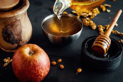 Natural honey is poured into a bowl, decorated with fruit and flowers