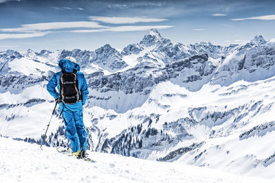 Man standing on snow covered landscape against sky