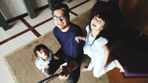 High angle portrait of father with cute daughters at home