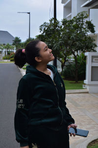 Side view of teenage girl standing against built structure