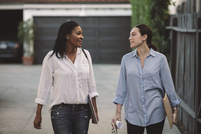 Female architects discussing while walking on footpath