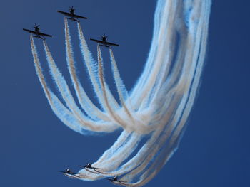 Low angle view of airshow against blue background