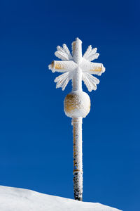 Low angle view of snow covered pole against clear blue sky