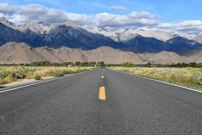 Scenic view of road amidst field against mountains and sky