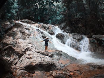 Woman standing at waterfall in forest