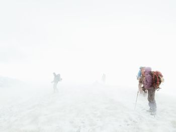 Rear view of people walking on snow covered landscape