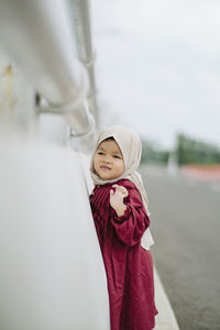 Portrait of young woman wearing hijab while standing against sky