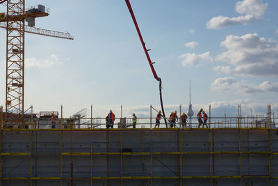 People working at construction site against sky