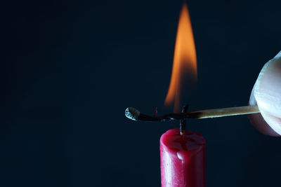Close-up of lit candle against black background