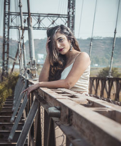 Portrait of young woman standing by railing