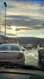 Cars on road against cloudy sky