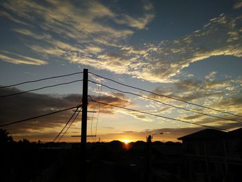 Low angle view of silhouette electricity pylon against sky during sunset