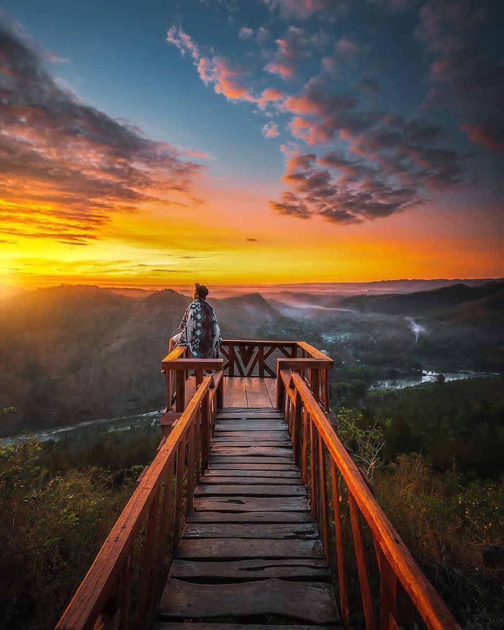 sky, sunset, cloud, nature, scenics - nature, beauty in nature, environment, architecture, landscape, water, horizon, land, travel, travel destinations, evening, sea, sunlight, tranquility, dusk, vacation, built structure, trip, holiday, sun, orange color, the way forward, outdoors, tranquil scene, mountain, wood, tourism, bridge, activity, adult, coast, railing, dramatic sky, one person, men, idyllic, beach, footpath, leisure activity, non-urban scene, reflection, transportation, pier, twilight, relaxation