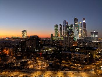 Illuminated buildings in city against clear sky at night