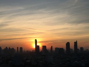 Silhouette buildings against sky during sunrise