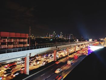 Light trails on bridge in city against sky at night