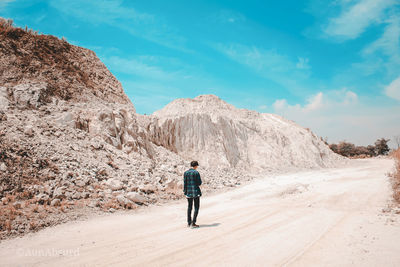 Rear view of man standing on mountain against sky