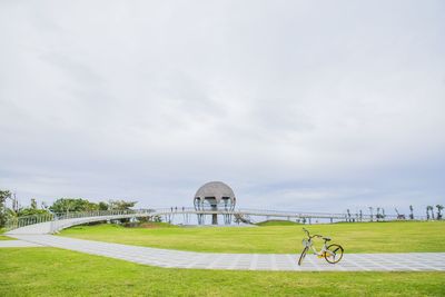 View of bicycle on grassy field against cloudy sky