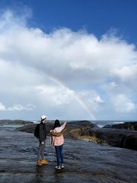 Friends standing on shore against sky