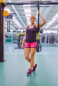 Full length of woman holding resistance band at gym