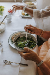 Woman's hands putting boiled mangetout on her plate