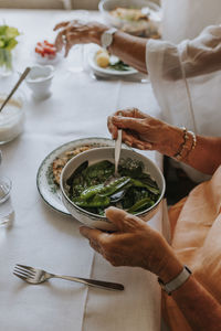 Woman's hands putting boiled mangetout on her plate