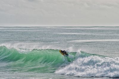 Man surfing in sea against sky