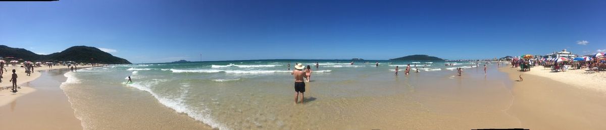 People on beach against clear blue sky